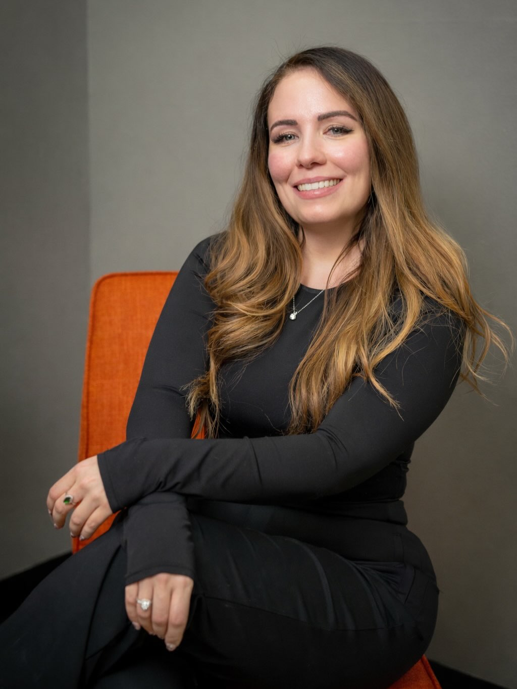 Caty Monterrosas, una pianista en Madison, Wisconsin, sonriendo mientras está sentada con un traje negro